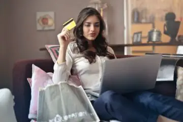 Woman on her computer holding a credit card wondering if she can make multiple payments a month towards her credit card debt