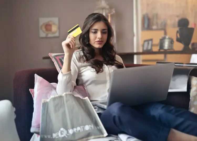 Woman on her computer holding a credit card wondering if she can make multiple payments a month towards her credit card debt